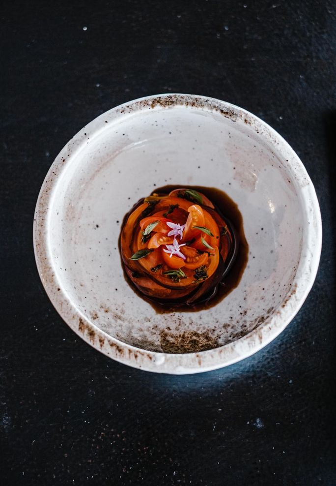 Spiral of thinly sliced tomato, dark sauce